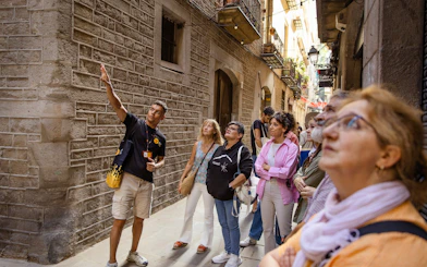 Tourists listening to a guide in a narrow street during a walking tour in Barcelona.