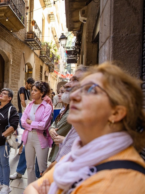 Tourists listening to a guide in a narrow street during a walking tour in Barcelona.