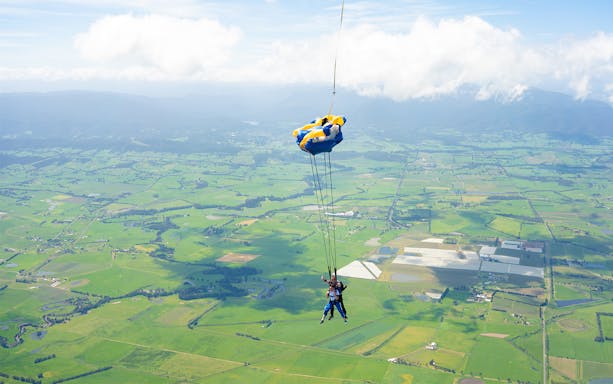 Tandem skydive over Yarra Valley, Melbourne, with green fields and mountains below.