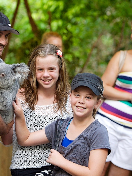 Person holding a koala with children at Kuranda wildlife park.