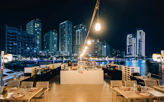 Seating area on Alexandra Sea Lounge Dhow Cruise with city skyline at night.