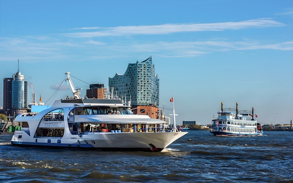 Cruise boats on the Elbe River with Elbphilharmonie in Hamburg.