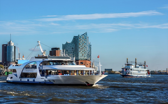 Cruise boats on the Elbe River with Elbphilharmonie in Hamburg.