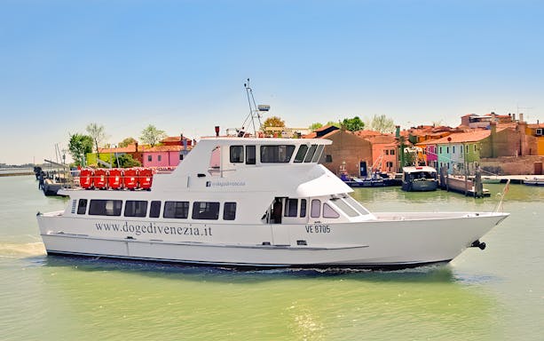 Boat cruising near colorful buildings in Burano, Venice, during afternoon tour from Punta Sabbioni.