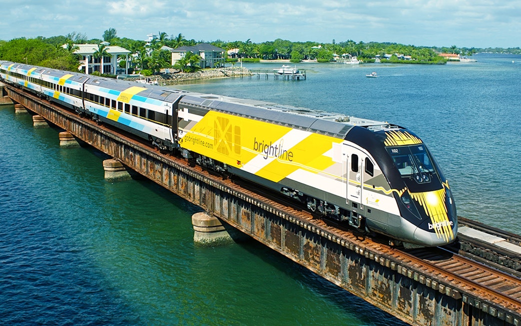 Brightline train crossing a bridge over water, Miami to Orlando route.