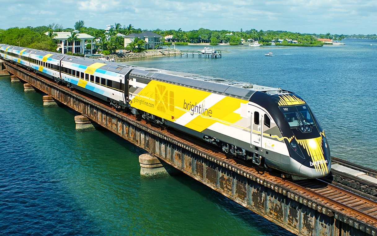Brightline train crossing a bridge over water, Miami to Orlando route.