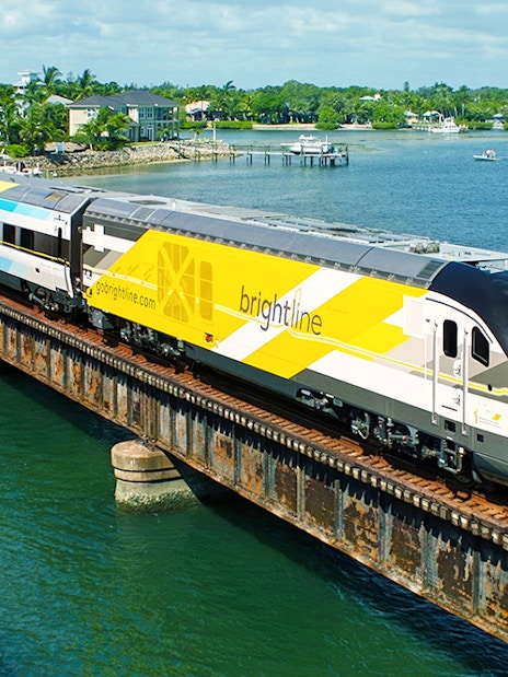 Brightline train crossing a bridge over water, Miami to Orlando route.