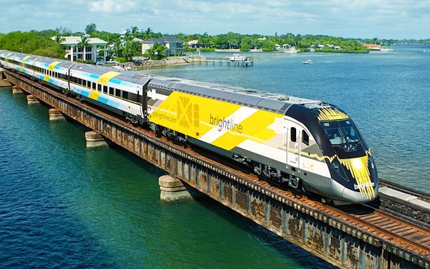 Brightline train crossing a bridge over water, Miami to Orlando route.