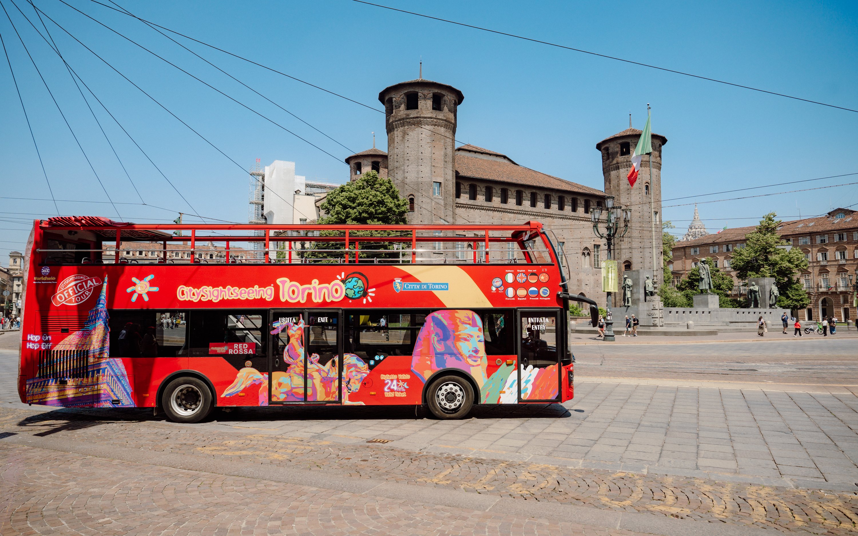 City Sightseeing Turin bus in front of historic castle in Turin, Italy.