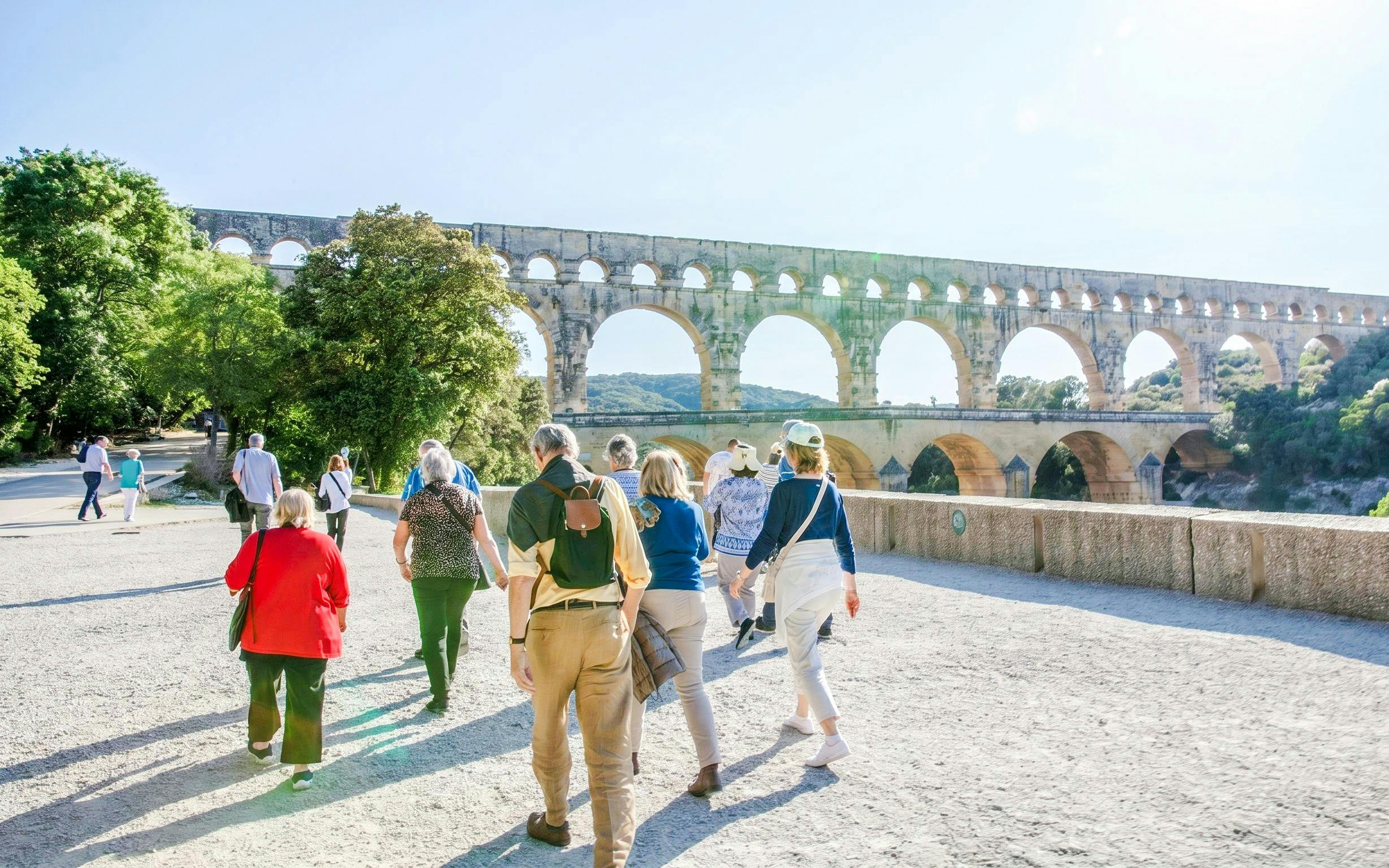 Visitors walking near Pont du Gard aqueduct in France.