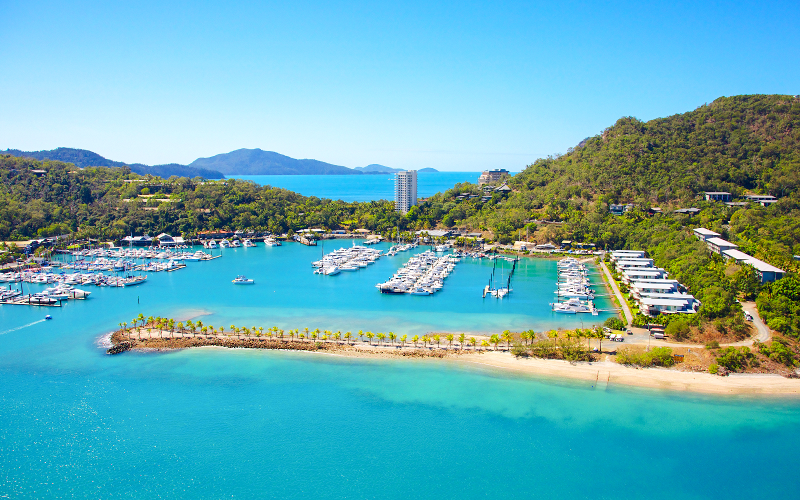 Hamilton Island marina with yachts and lush hills in Whitsundays, Australia.