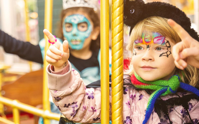 Children with face paint enjoying a ride at Tivoli Gardens Halloween event in Copenhagen.