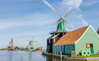 Windmills and traditional houses by the water in Zaanse Schans, Netherlands.