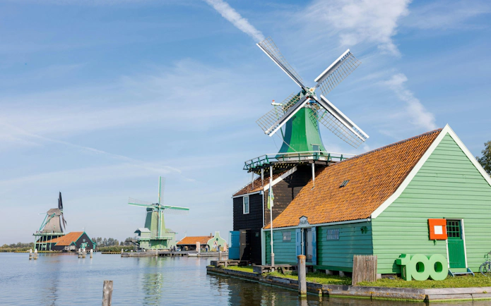 Windmills and traditional houses by the water in Zaanse Schans, Netherlands.