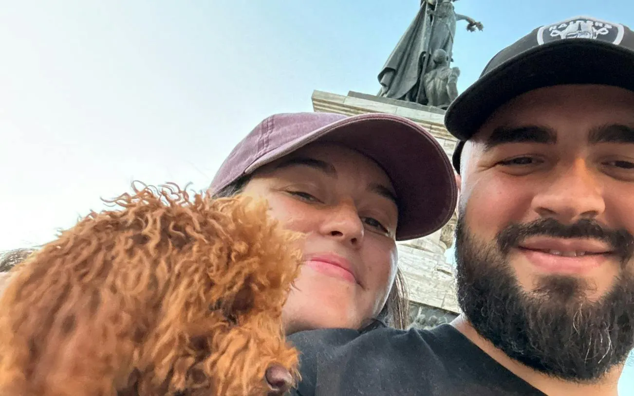 Couple with dog in front of a statue during Bucharest Romantic Cotroceni city exploration game.