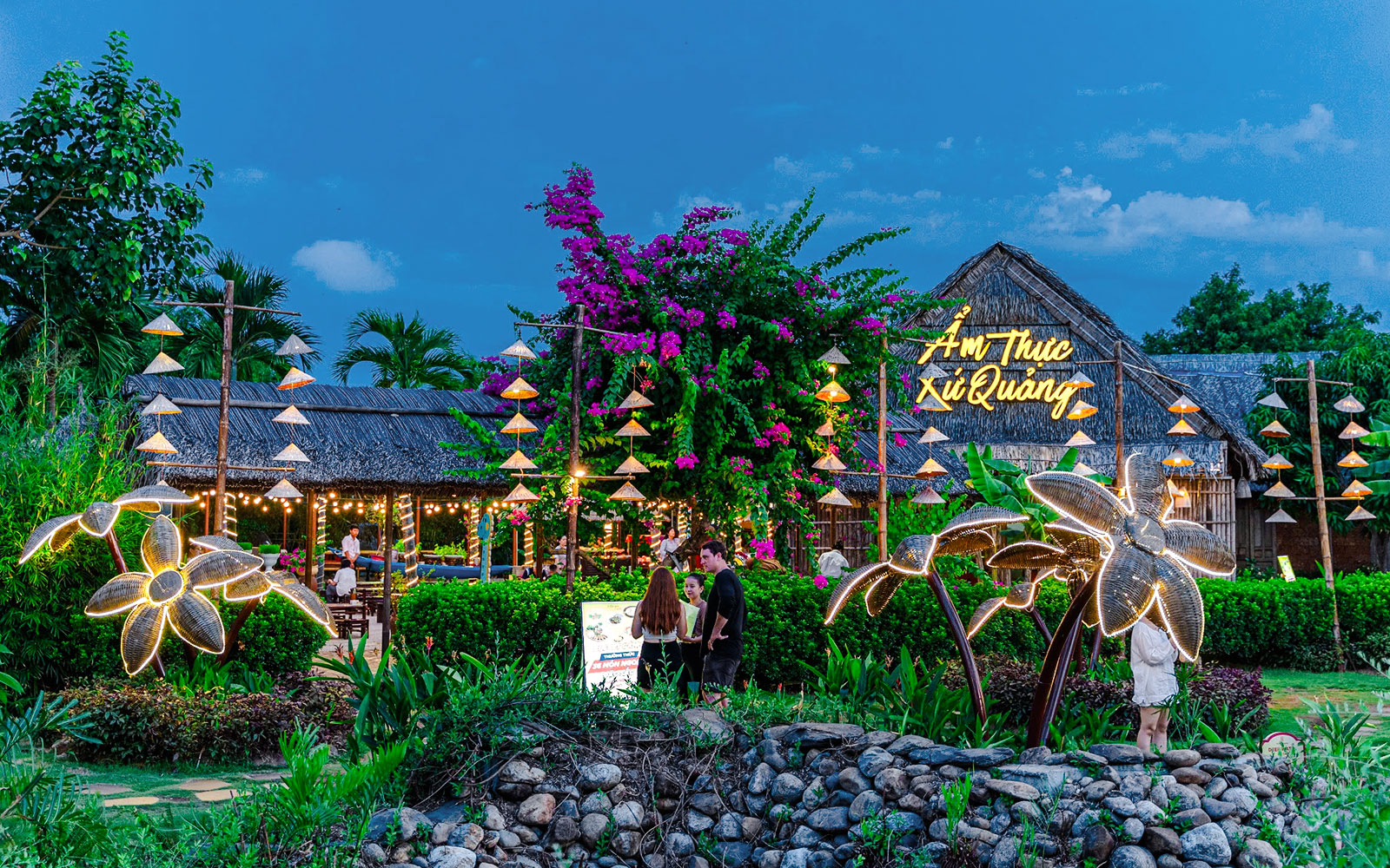 Dining area at Hoi An Memories with illuminated decorations and traditional thatched roof.