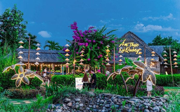 Dining area at Hoi An Memories with illuminated decorations and traditional thatched roof.
