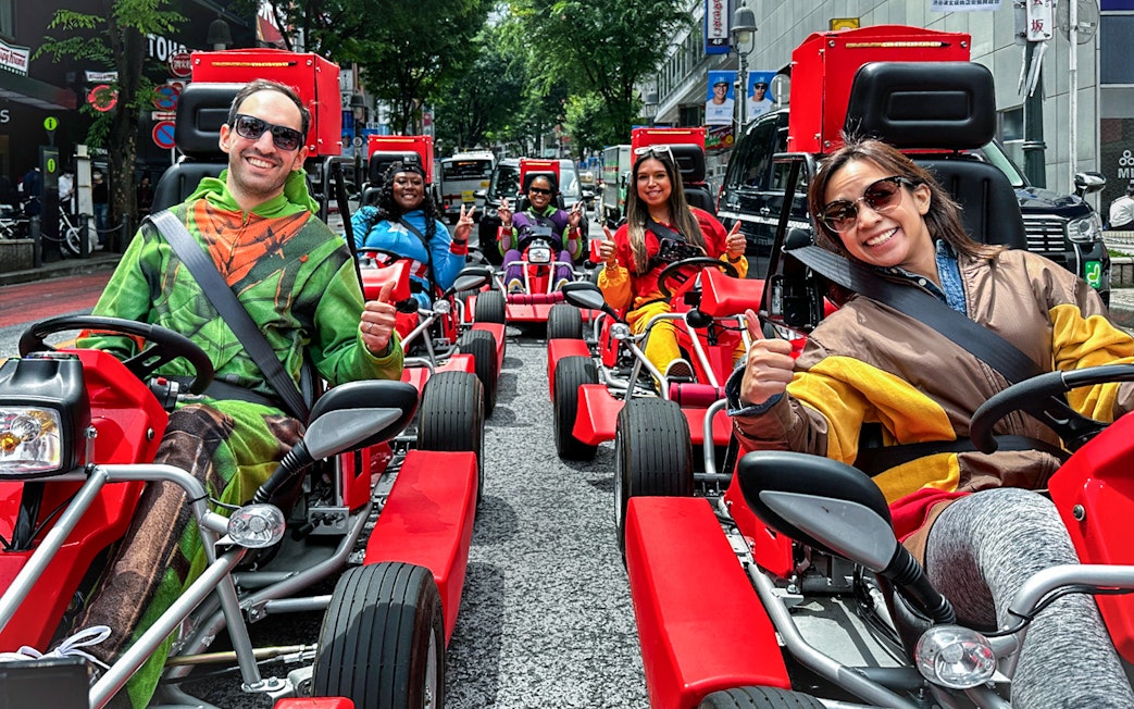 Participants in costumes driving go-karts on a Shibuya street tour.