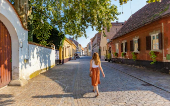 Woman walking down a cobblestone street in Varazdin's historical center with colorful houses.