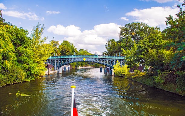 Landwehrkanal cruise view of a bridge surrounded by lush trees in Berlin.