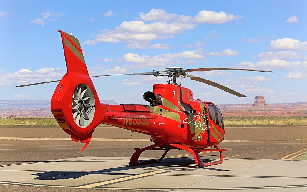 Helicopter on tarmac with desert landscape, preparing for Horseshoe Bend aerial tour.
