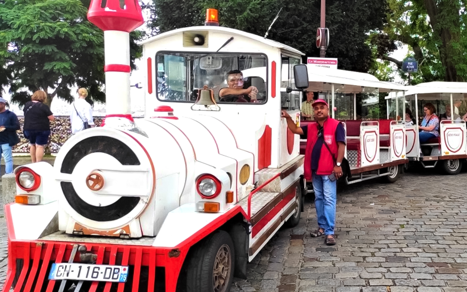 Montmartrain with tourists on cobblestone street in Paris.