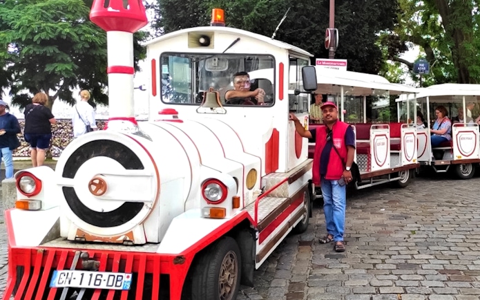 Montmartrain with tourists on cobblestone street in Paris.