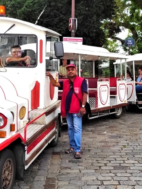 Montmartrain with tourists on cobblestone street in Paris.