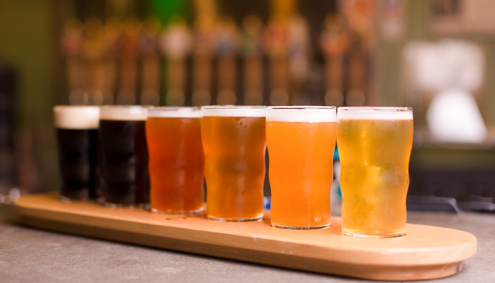 beer taster tray with six different beers on a wooden board.