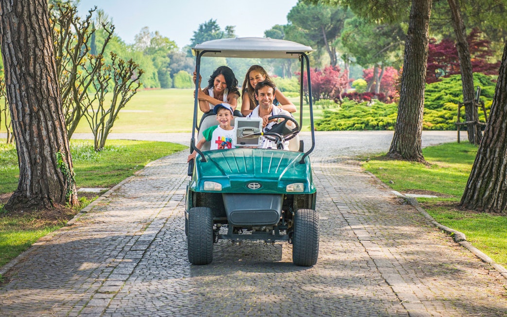 Family riding a golf cart through Parco Giardino Sigurtà, Italy.