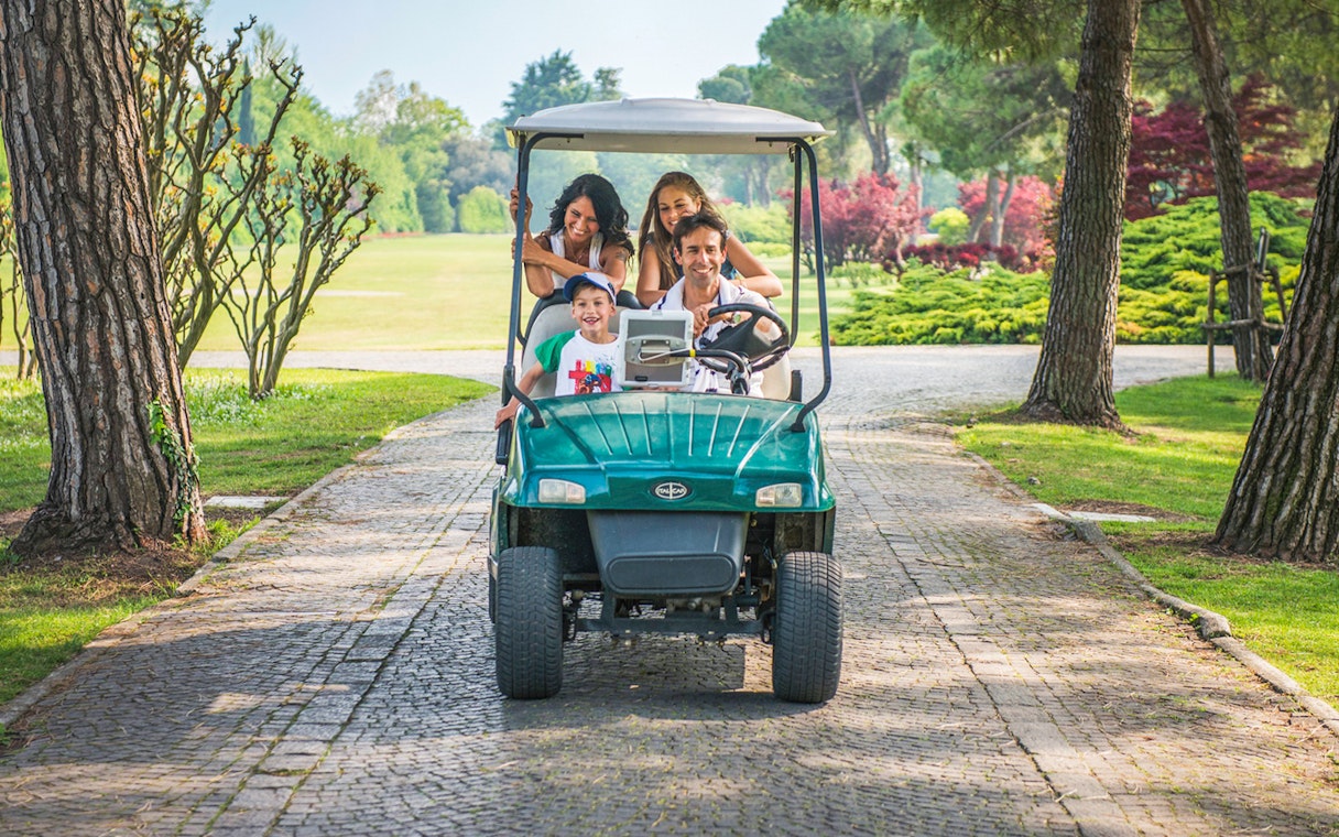 Family riding a golf cart through Parco Giardino Sigurtà, Italy.