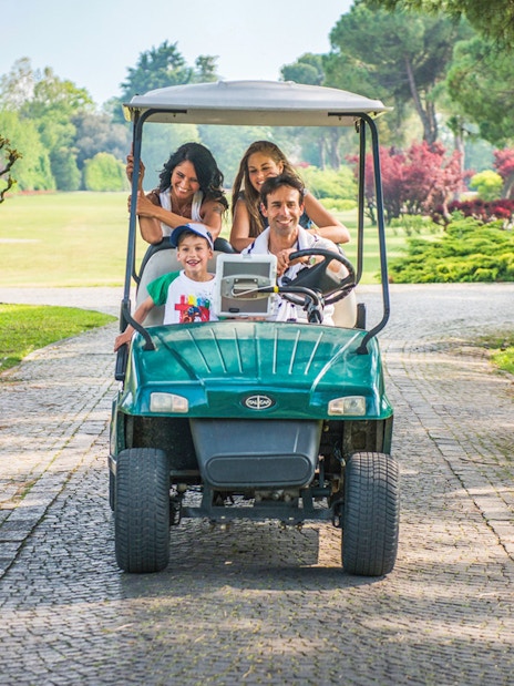 Family riding a golf cart through Parco Giardino Sigurtà, Italy.