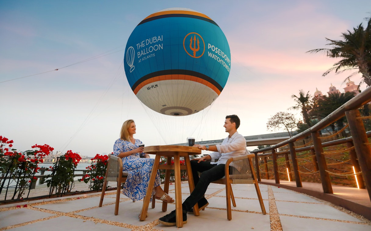 Couple enjoying a drink under The Dubai Balloon at Atlantis, Dubai.
