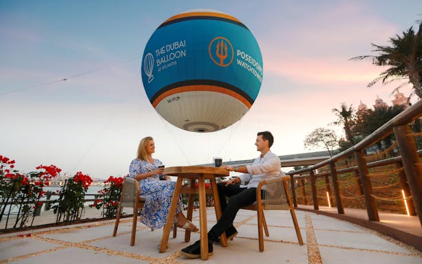 Couple enjoying a drink under The Dubai Balloon at Atlantis, Dubai.