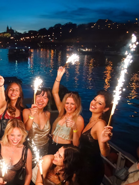 Group celebrating with sparklers on a boat cruise at dusk.