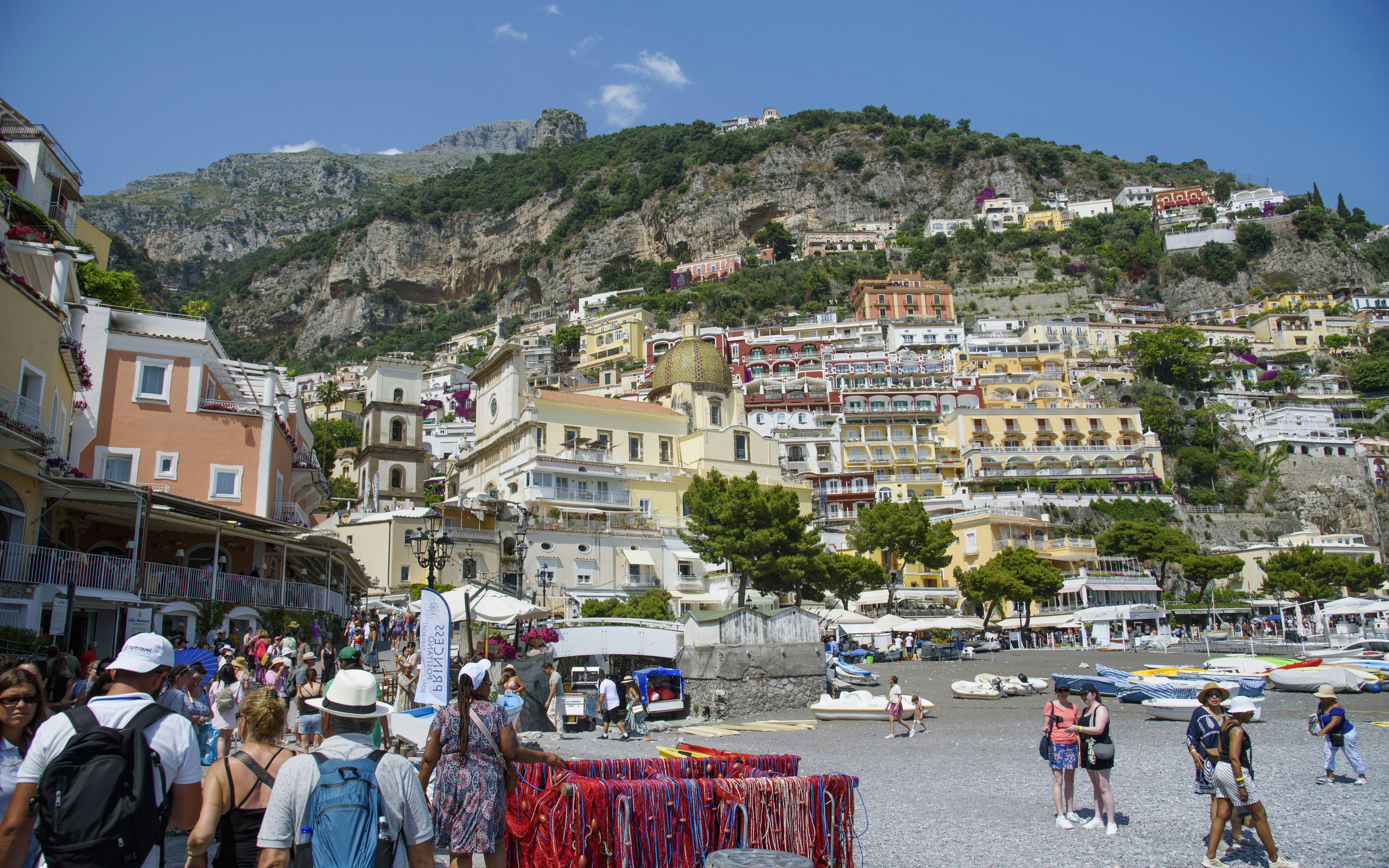 Crowded beach and colorful hillside buildings in Positano on the Amalfi Coast.