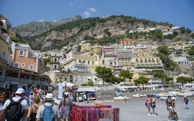 Crowded beach and colorful hillside buildings in Positano on the Amalfi Coast.