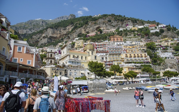 Crowded beach and colorful hillside buildings in Positano on the Amalfi Coast.