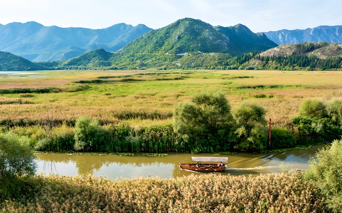 Wooden boat on guided sightseeing tour through Lake Skadar's lush landscape.
