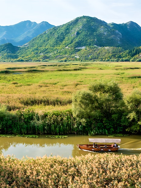 Wooden boat on guided sightseeing tour through Lake Skadar's lush landscape.