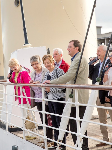 Tourists enjoying a guided tour on a ship deck.