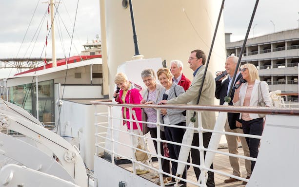 Tourists enjoying a guided tour on a ship deck.