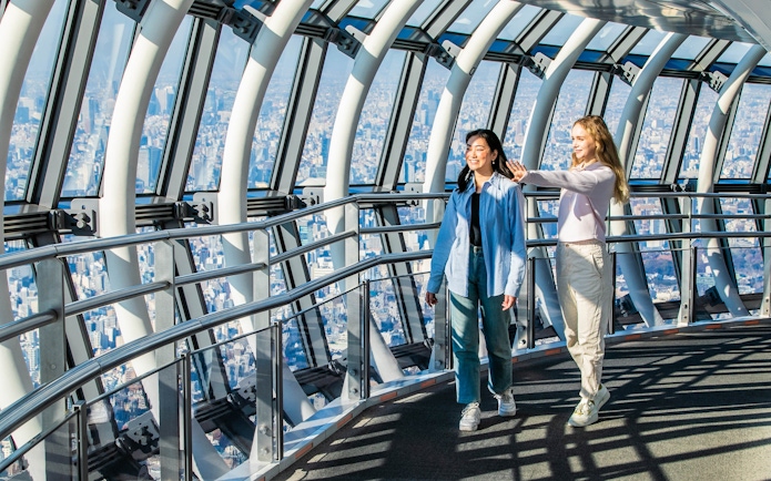 Tourists walking inside Tokyo Skytree galleria with city view.