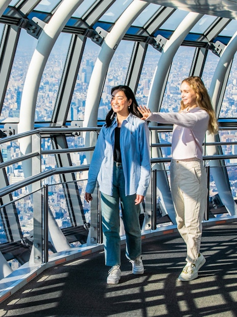 Tourists walking inside Tokyo Skytree galleria with city view.