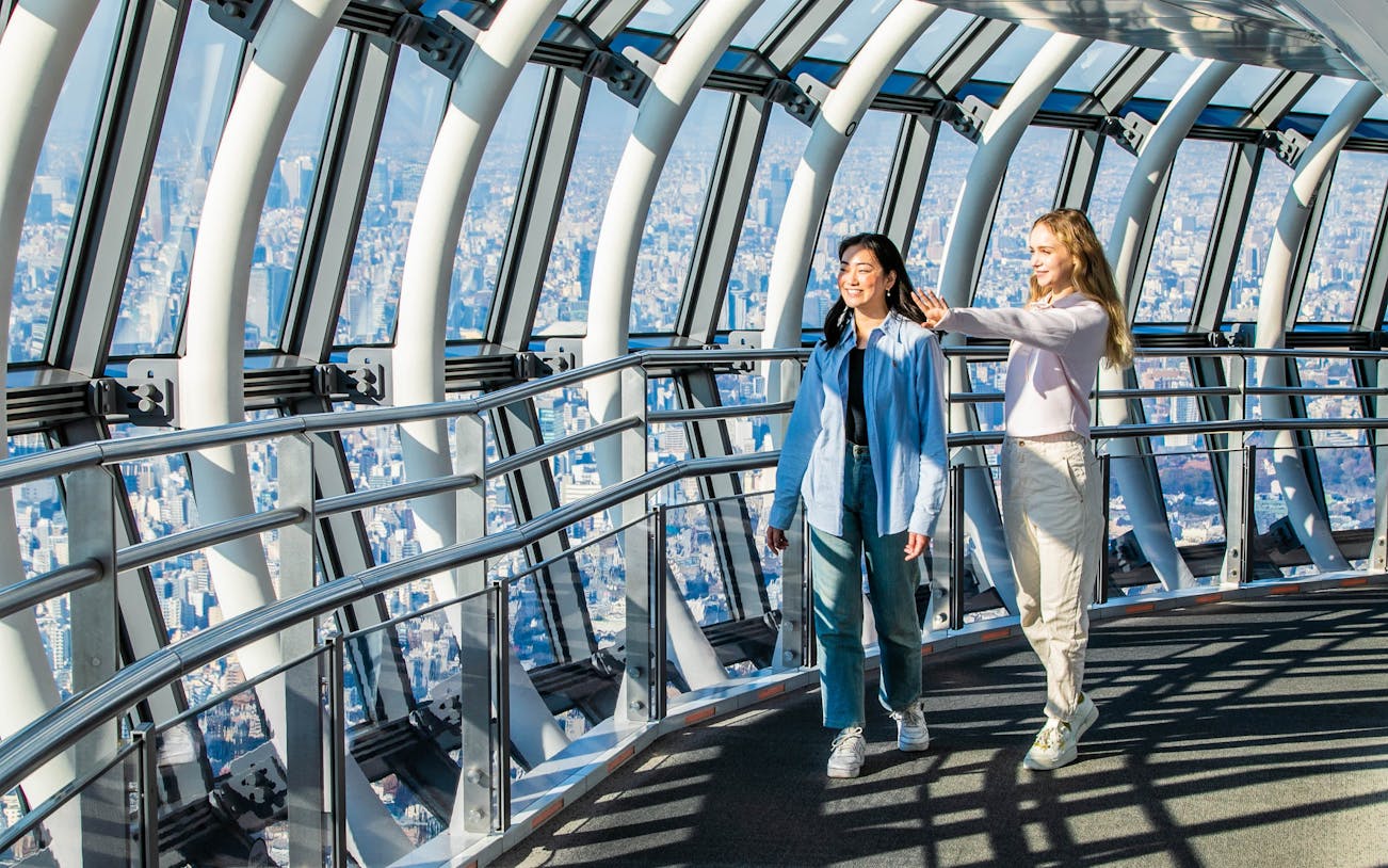 Tourists walking inside Tokyo Skytree galleria with city view.
