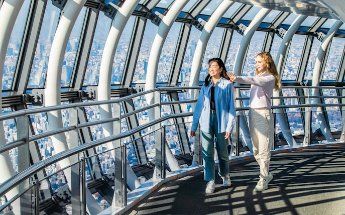 Tourists walking inside Tokyo Skytree galleria with city view.
