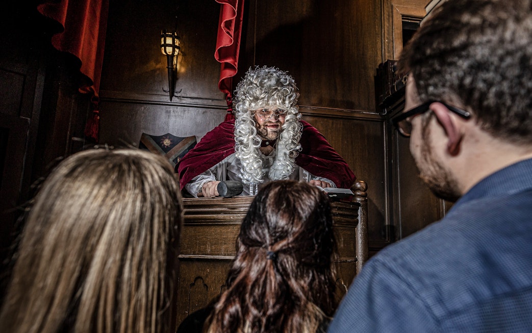 Judge in period costume presiding over courtroom scene at York Dungeon.