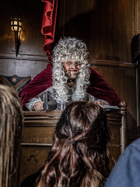 Judge in period costume presiding over courtroom scene at York Dungeon.