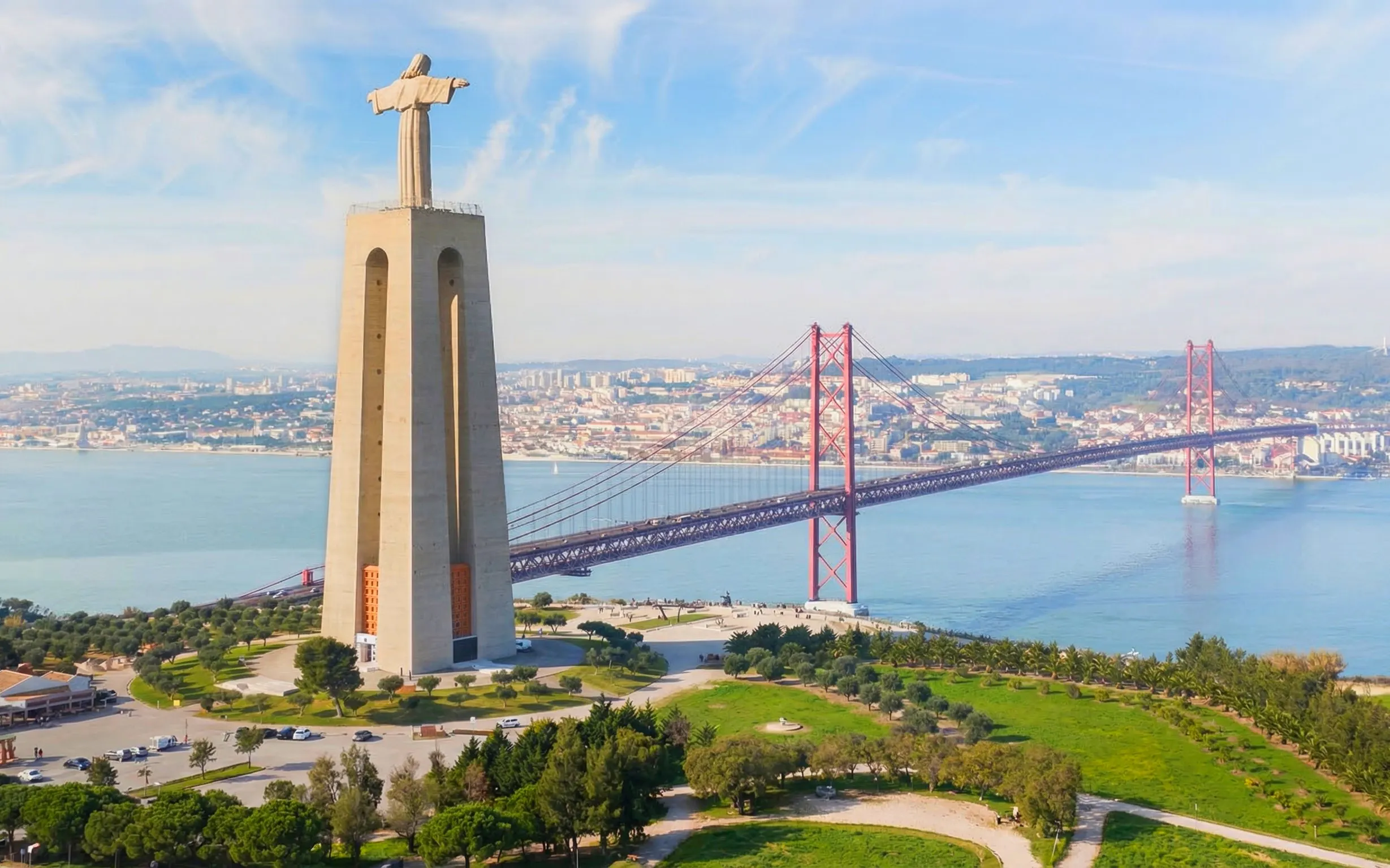 Sanctuary of Christ the King with 25 de Abril Bridge in Lisbon, Portugal.