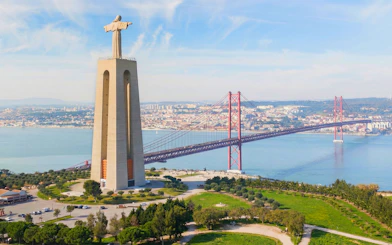 Sanctuary of Christ the King with 25 de Abril Bridge in Lisbon, Portugal.